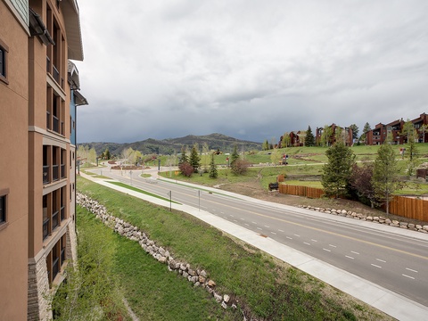 The property is located in a scenic mountain community with rolling hills, evergreen trees, and neighboring residences, offering a peaceful setting surrounded by natural beauty and local charm.