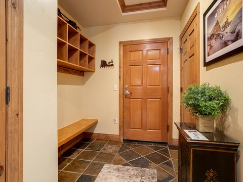 Welcoming entryway with natural light from a skylight, warm wood tones, built-in storage cubbies, and slate tile flooring—perfect for kicking off your snow boots after a mountain adventure.
