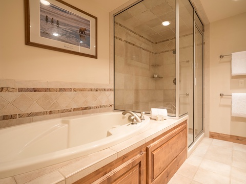 Your spa-like bathroom features a deep soaking tub and walk-in shower with elegant tile work, perfect for unwinding after mountain adventures.