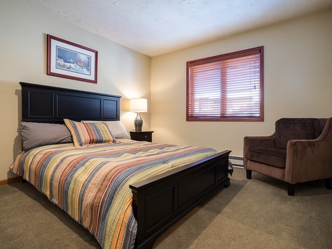Your peaceful bedroom retreat features a cozy bed with colorful linens, a comfortable reading chair, and soft natural light filtering through the window—perfect for restful nights.