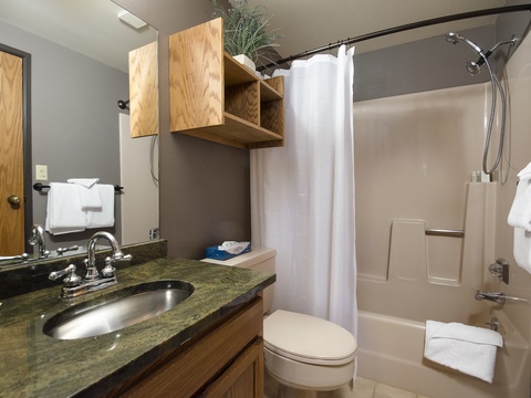Your private bathroom has everything you need—plush towels, a clean shower/tub combo, and a spacious vanity with warm wood finishes that invite you to unwind.