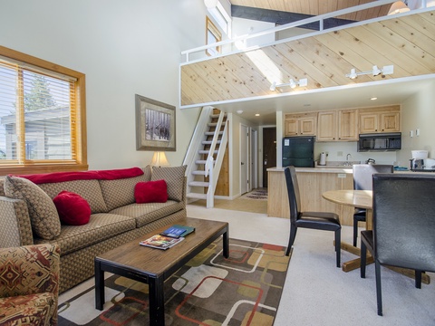 Your bright, open-plan retreat features a cozy living area, fully equipped kitchen, and loft space above—perfect for unwinding after a day of adventure.