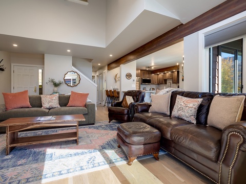 Sink into supple leather seating and unwind in this sun-drenched living space featuring vaulted ceilings, rich wood beams, and mountain views—your perfect retreat after a day exploring.
