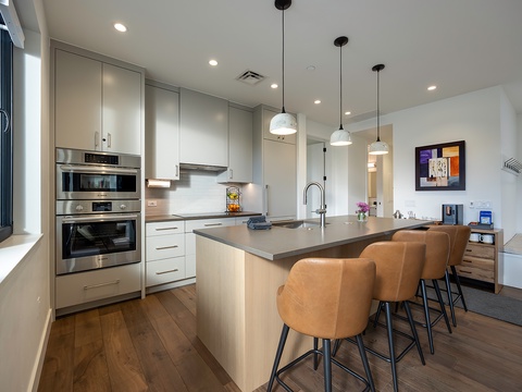 Gather around the spacious kitchen island where modern pendant lights illuminate sleek countertops and stainless steel appliances. Whether prepping meals or sharing stories over coffee, you'll find everything you need in this bright, inviting space.