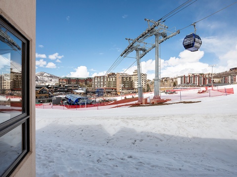 A ski resort base area with gondola access, surrounded by mountain residences and snowy slopes, offering convenient proximity to winter activities.