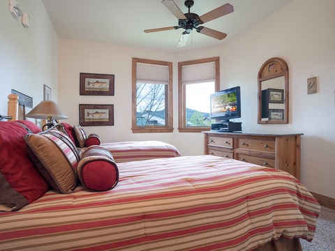 Drift off in your cozy bedroom, where a plush bed awaits beneath a gentle ceiling fan and mountain views peek through the windows.