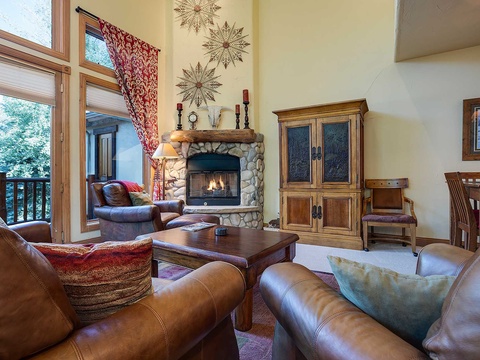 Unwind in your cozy living room with plush leather seating, a warm stone fireplace, and mountain views just outside. Perfect for relaxing after a day of adventure.