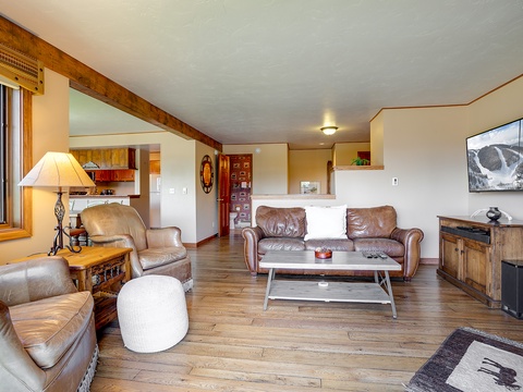 Unwind in your spacious living room with cozy leather seating, rustic wood beams, and a flat-screen TV perfect for mountain movie nights after a day of adventure.