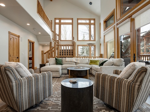 Sink into plush seating and feel at home in this sun-filled living space with soaring windows that frame snowy alpine views, perfect for unwinding after your mountain adventures.