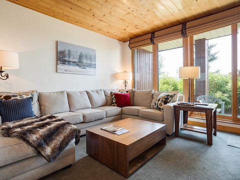 Unwind in your spacious living room where warm wood ceilings and floor-to-ceiling windows frame stunning garden views. Sink into the plush sectional and feel instantly at home.