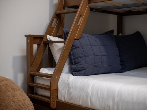 Your cozy bunk beds await, dressed in crisp white linens and inviting navy pillows—perfect for restful nights after adventurous days.