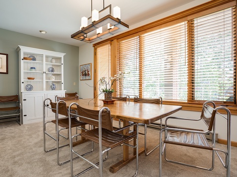 Gather around the warm wood dining table where natural light filters through elegant blinds, perfect for morning coffee or sharing meals with loved ones in this thoughtfully designed space.