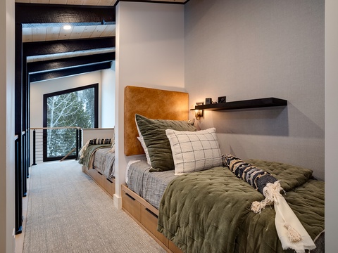 Your cozy bedroom awaits with plush bedding, warm textures, and a peaceful view of the trees—your perfect retreat after a day of mountain adventure.