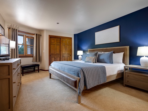 Sink into this inviting bedroom with crisp linens and a calming deep blue accent wall, your perfect retreat after a day of adventure. Soft lighting and cozy textures create a peaceful space to relax and recharge.