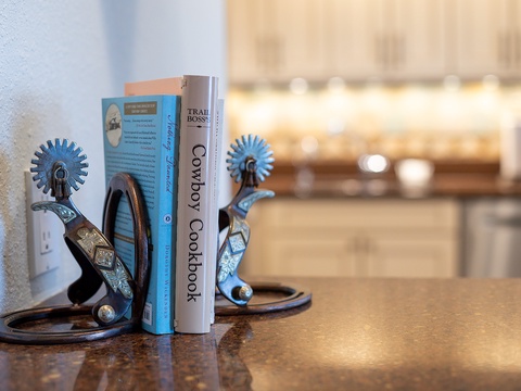 Unique western-style bookends add character to your space, holding cowboy cookbooks on the granite countertop near the kitchen.