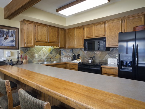 Your fully equipped kitchen invites you to gather and create, with ample counter space, modern appliances, and warm wood tones perfect for preparing meals together.