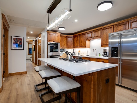 Picture yourself preparing meals in this stunning chef's kitchen with rich wood cabinetry, sleek stainless appliances, and a spacious island perfect for cooking and gathering together.