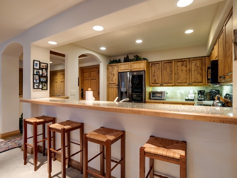 Pull up a seat at your breakfast bar and savor morning coffee while planning the day's adventures. This inviting open kitchen features warm wood cabinetry, granite countertops, and modern appliances ready for your culinary creations.