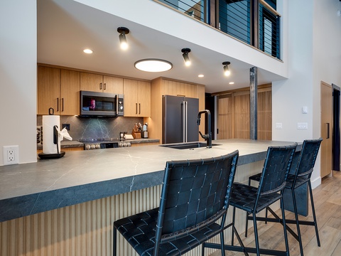 Gather at your spacious kitchen island, where modern design meets warm wood tones. Prep meals with sleek appliances and dine together with seating for everyone under bright, welcoming light.