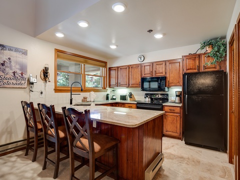 Gather around this inviting kitchen island where your group can share meals and laughter. Rich wood cabinetry, modern appliances, and ample counter space make cooking a pleasure in your mountain retreat.