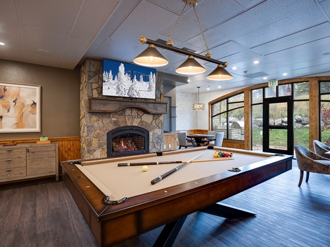 Challenge your travel companions to a friendly game in this inviting space, complete with a cozy fireplace and scenic views of the lush grounds beyond the expansive windows.
