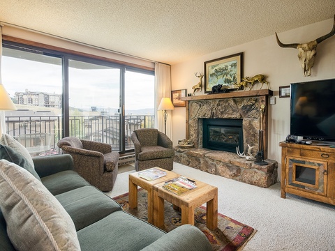 Settle into this inviting living room where rustic charm meets comfort. Relax by the stone fireplace, enjoy your favorite shows, and take in sweeping views from your private balcony.