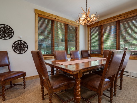 Gather around this handsome dining table for shared meals and stories, with rustic charm highlighted by the antler chandelier and warm wood accents that invite memorable moments together.