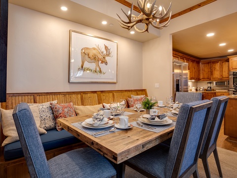 Gather around this warm dining space featuring rustic wood accents, comfortable seating, and a stunning antler chandelier overhead. The open layout flows into a fully-equipped kitchen, perfect for memorable meals together.