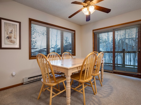 Gather your group around this welcoming dining table, with natural light streaming through the windows and a gentle ceiling fan overhead, perfect for sharing meals and making memories together.