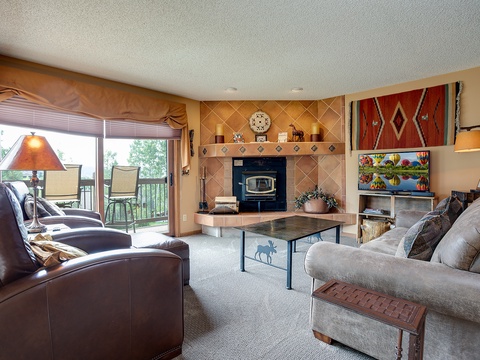 Unwind in your cozy living room, where plush seating and a warm fireplace invite you to relax after a day of adventure, with natural light and patio access.
