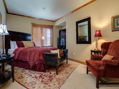 Sink into the plush bed with luxurious burgundy linens and rest in your cozy wingback chair as warm lamplight fills this elegant retreat.