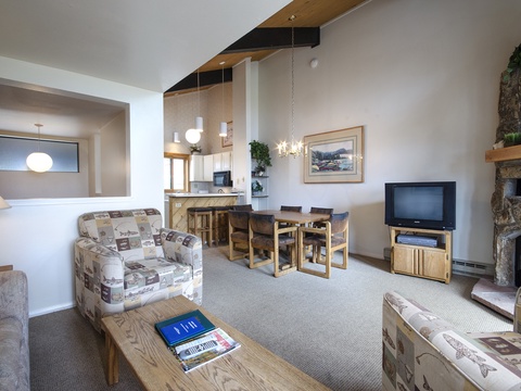 Your spacious living and dining area features soaring ceilings, a cozy stone fireplace, and comfortable seating perfect for relaxing after a day of mountain adventures.