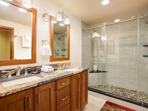 Step into your beautifully appointed bathroom with dual vanities, elegant granite countertops, and a spacious walk-in shower featuring modern glass doors and refined tilework.