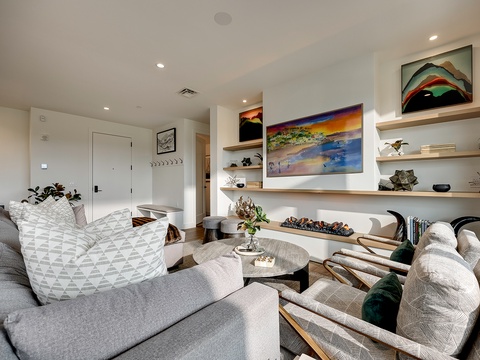 Settle into plush, modern seating where thoughtful design meets comfort. Open shelving displays curated pieces, while artwork and soft lighting create a welcoming retreat for your relaxation.