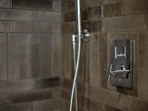 Rinse away the day under a sleek rainfall showerhead with modern chrome fixtures and warm neutral tiling for your comfort.