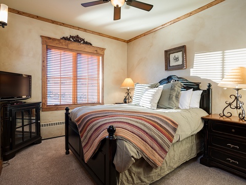 Drift into restful sleep in this cozy bedroom featuring a plush queen bed with soft linens, warm bedside lamps, and a ceiling fan to keep you comfortable year-round.