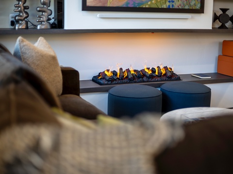 Curl up on the plush sofa and enjoy the warmth of your modern fireplace. The inviting living space combines comfort with contemporary style, perfect for relaxing evenings in.