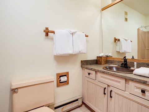 Your bathroom features a spacious vanity with granite countertop, fresh white towels, and thoughtful wooden accents that add warmth to this bright, clean space perfect for unwinding.