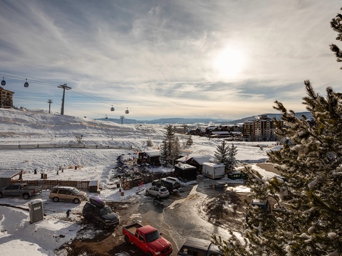 Alpine ski resort nestled in snowy mountains with ski lifts, gondolas, and village buildings framing the winter landscape under a dramatic sky.