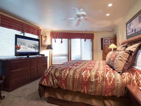 Sink into plush bedding and unwind in your spacious bedroom, where warm textures, a flat-screen TV, and mountain views through large windows create your perfect retreat.