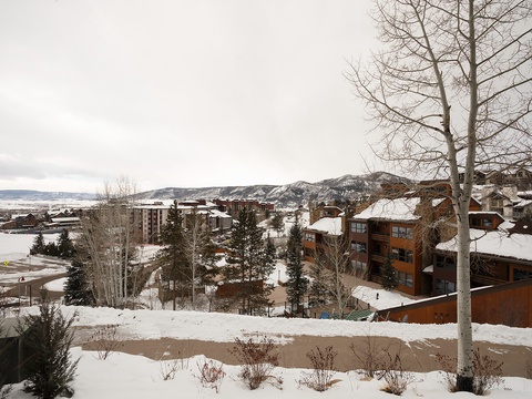 Snow-covered mountain resort village with ski lodges nestled among evergreens and winter terrain, offering scenic valley and hillside views beyond the property.