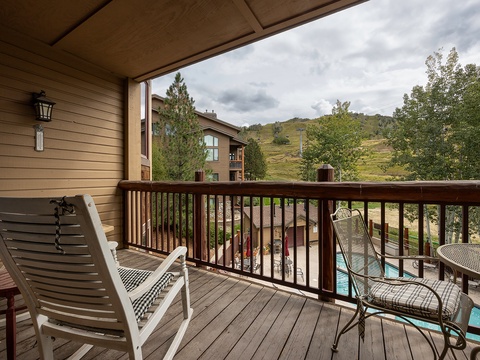 Step onto your private balcony and take in the crisp mountain air as you gaze at the gentle slopes and evergreens stretching beyond the pool area—your peaceful retreat awaits.