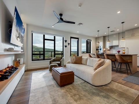 Sink into the plush sofa and take in sweeping mountain vistas through expansive windows. The open-plan living area flows seamlessly into a fully-equipped kitchen, while modern finishes and warm wood tones create your perfect mountain retreat.