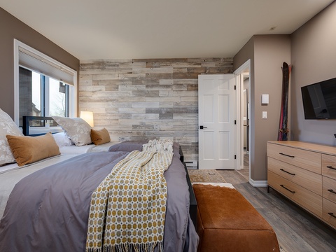 Sink into plush bedding and enjoy your favorite shows from the comfort of this inviting bedroom. Warm wood accents and natural light create a peaceful retreat.