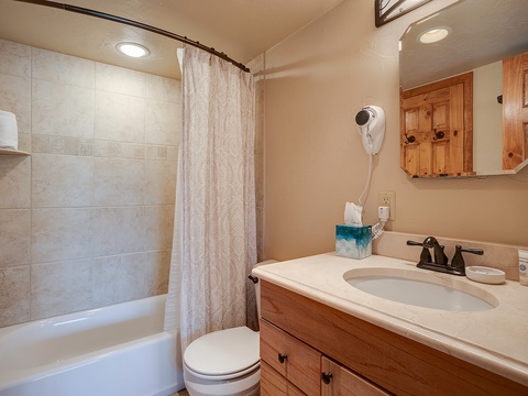 Your private bathroom combines comfort and convenience with a walk-in shower, warm tiled walls, spacious vanity, and cozy wood accents to help you feel right at home.