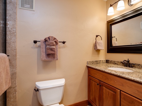 Your private bathroom features warm wood cabinetry, granite countertops, and plush towels ready for your arrival—simple comforts to make you feel right at home.