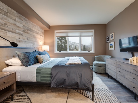 Sink into this cozy bedroom where rustic wood meets mountain views. Your space features a plush bed, modern TV, and scenic windows that frame natural beauty.