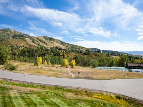 A mountain resort community featuring ski runs, tennis courts, and forested foothills beneath expansive autumn skies.