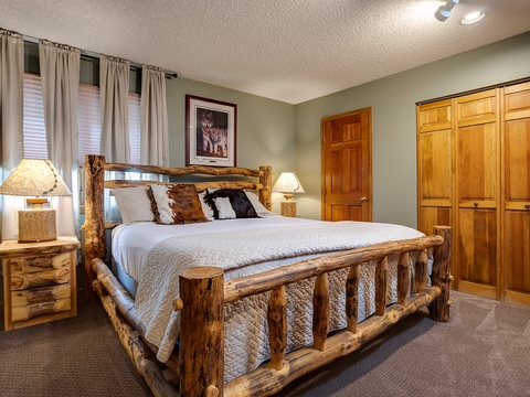 Sink into the rustic charm of your handcrafted log bed, flanked by warm wood accents and soft lamplight—your cozy mountain retreat awaits.