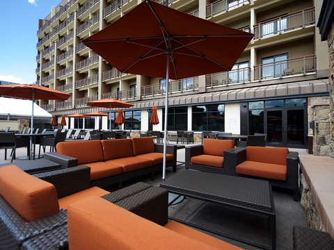 This inviting outdoor lounge area with property structure in the background offers a perfect setting for relaxation. Comfortable seating and shaded areas provide a welcoming space to unwind during your stay.